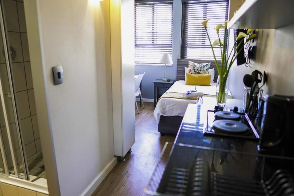 Une chambre d’hôtel moderne équipée d’un lit, d’un petit bureau, d’un piano et d’une fenêtre avec des stores.