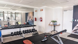 A gym with exercise equipment, a bench press, dumbbells, and a fire extinguisher. - 106 on Adderley Accommodation (Cape Town)