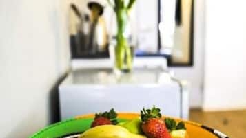 A fruit bowl on a table with a kitchen in the background.