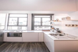 A modern kitchen with a built-in microwave, a sink, and a window overlooking the city.