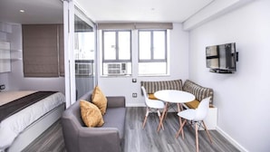 A modern, well-lit room with a sofa, a small dining table, and a TV mounted on the wall. - 106 on Adderley Accommodation (Cape Town)