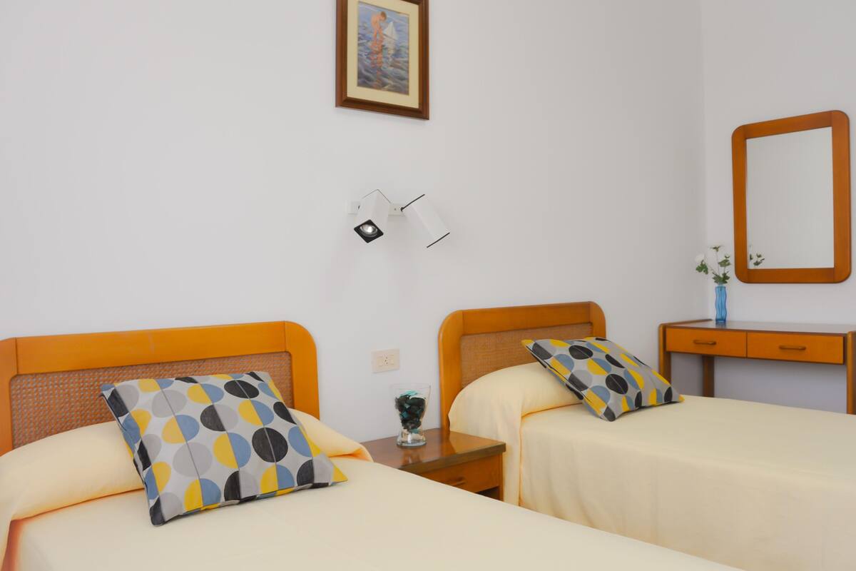 Ein Hotelzimmer mit zwei Betten, einem Nachttisch, einem Spiegel und einem Bild an der Wand.