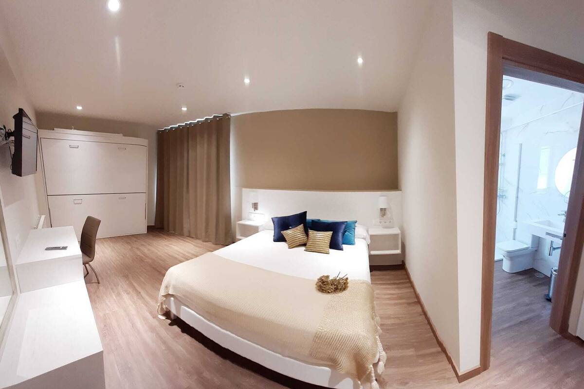 Ein modernes Hotelzimmer mit einem großen Bett, einem Schreibtisch und einem Kleiderschrank.