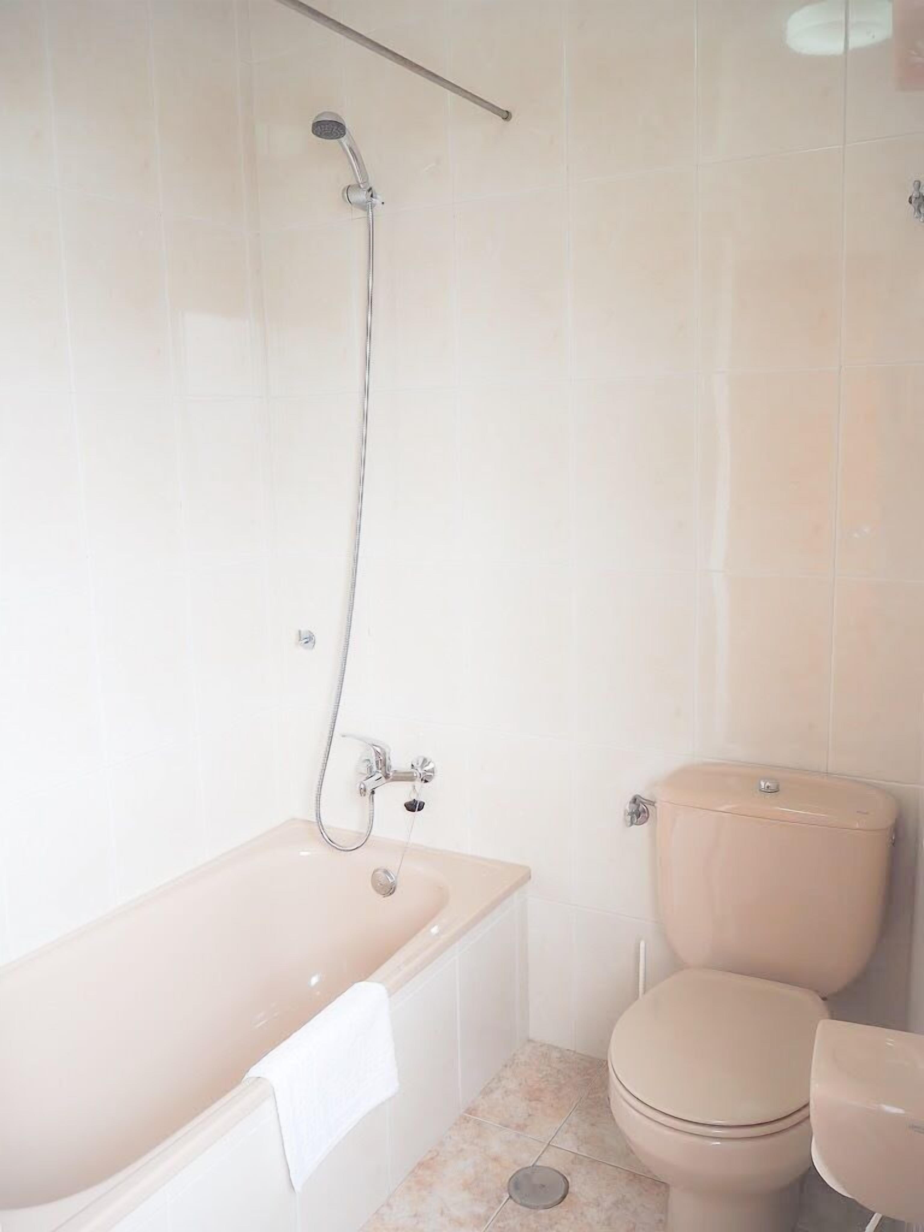 A bathroom with a bathtub, toilet, and a showerhead.