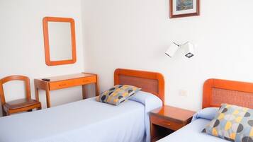 A hotel room with two beds, a desk, a chair, a mirror, and a picture on the wall.