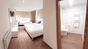 A hotel room with two beds, a bathroom with a toilet and a radiator, and a hallway with a radiator and a mirror.