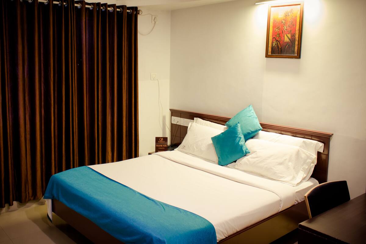 A hotel room with a bed, a desk, and a curtain.