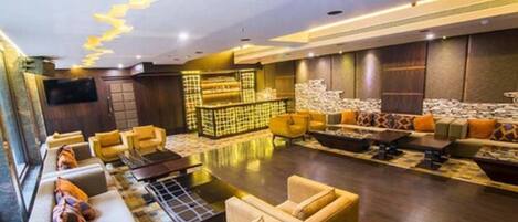 A spacious lobby with a long reception desk, multiple seating areas, and a modern ceiling design.
