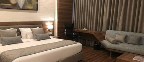 A hotel room with a bed, a sofa, a desk, and a chair.