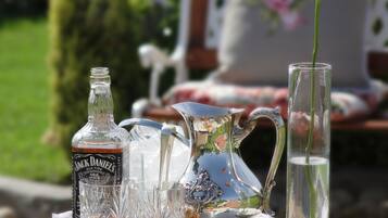 Mesa al aire libre con jarra, botella, vaso y rosa.