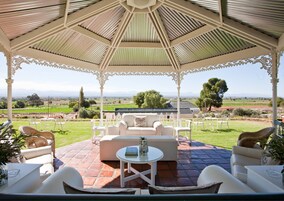 A covered outdoor seating area with a view of a green landscape and distant mountains.