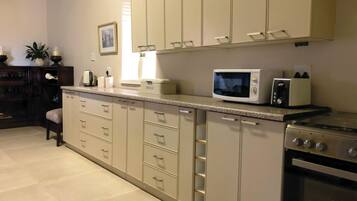 A kitchen with a microwave, toaster, and a bread box on the counter. There are cabinets with drawers and a stove.