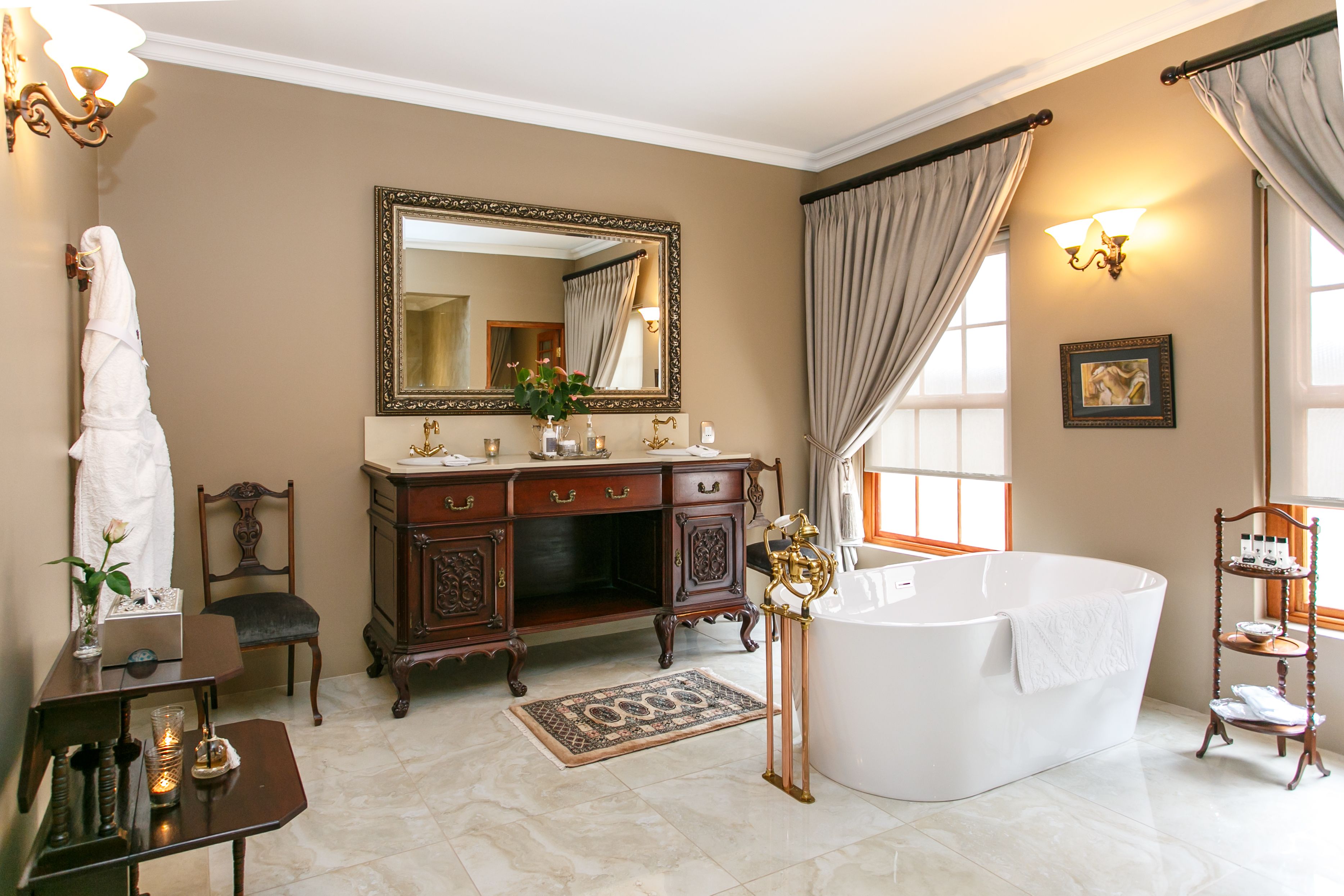Un baño amplio con una bañera independiente, un espejo grande y un tocador con un mueble con detalles dorados.