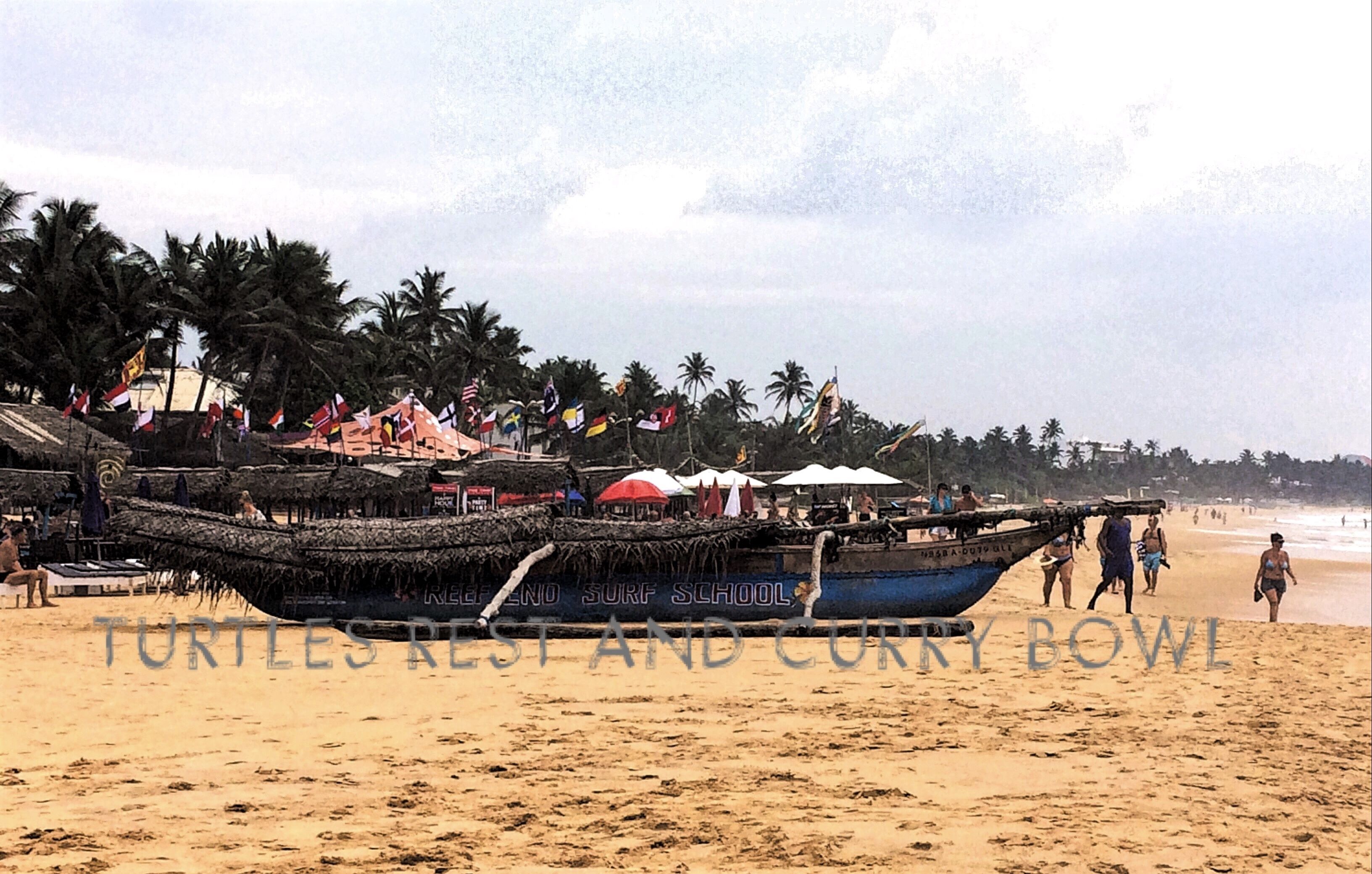 Une plage avec un grand bateau sur lequel on peut lire l’inscription « Turtle Rest and Curry Bowl » et plusieurs parasols.
