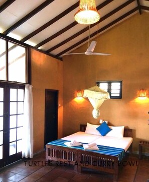 A bedroom with a bed, a ceiling fan, and two wall-mounted lamps. - Turtles Rest and Curry Bowl (Hikkaduwa)