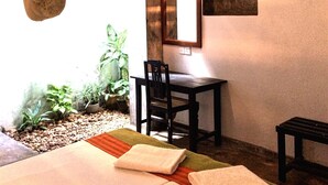 A room with a bed, a desk, a chair, a hanging light fixture, and a ceiling fan. - Turtles Rest and Curry Bowl (Hikkaduwa)
