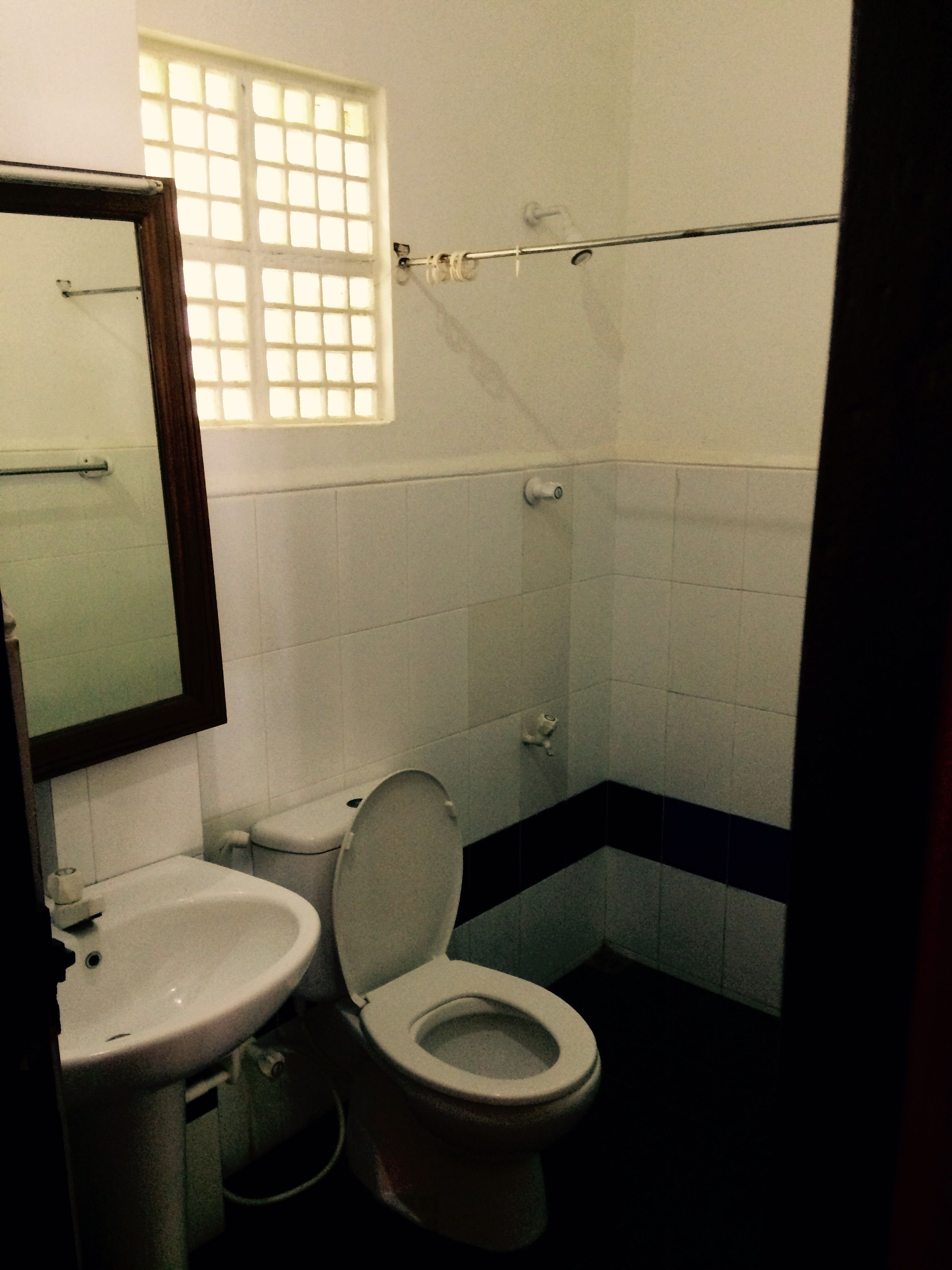 Un baño con inodoro, lavabo y una ventana con barrotes.