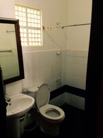 Un baño con inodoro, lavabo y una ventana con barrotes.