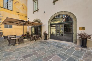 Un'area patio esterna con pavimento in pietra, mobili in vimini e piante in vaso.