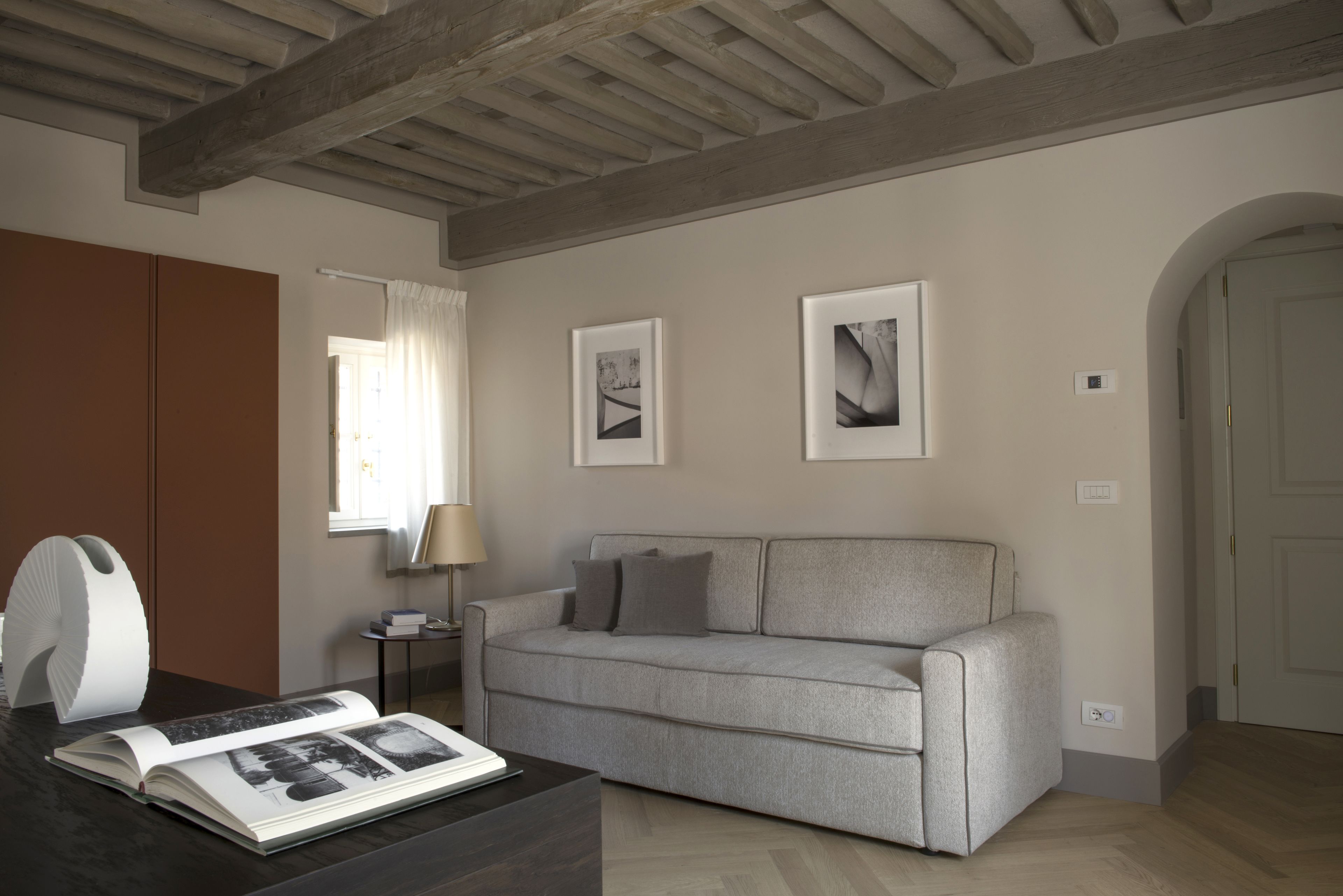 A modern living room with a grey sofa, a coffee table with a magazine, and a white sculpture.