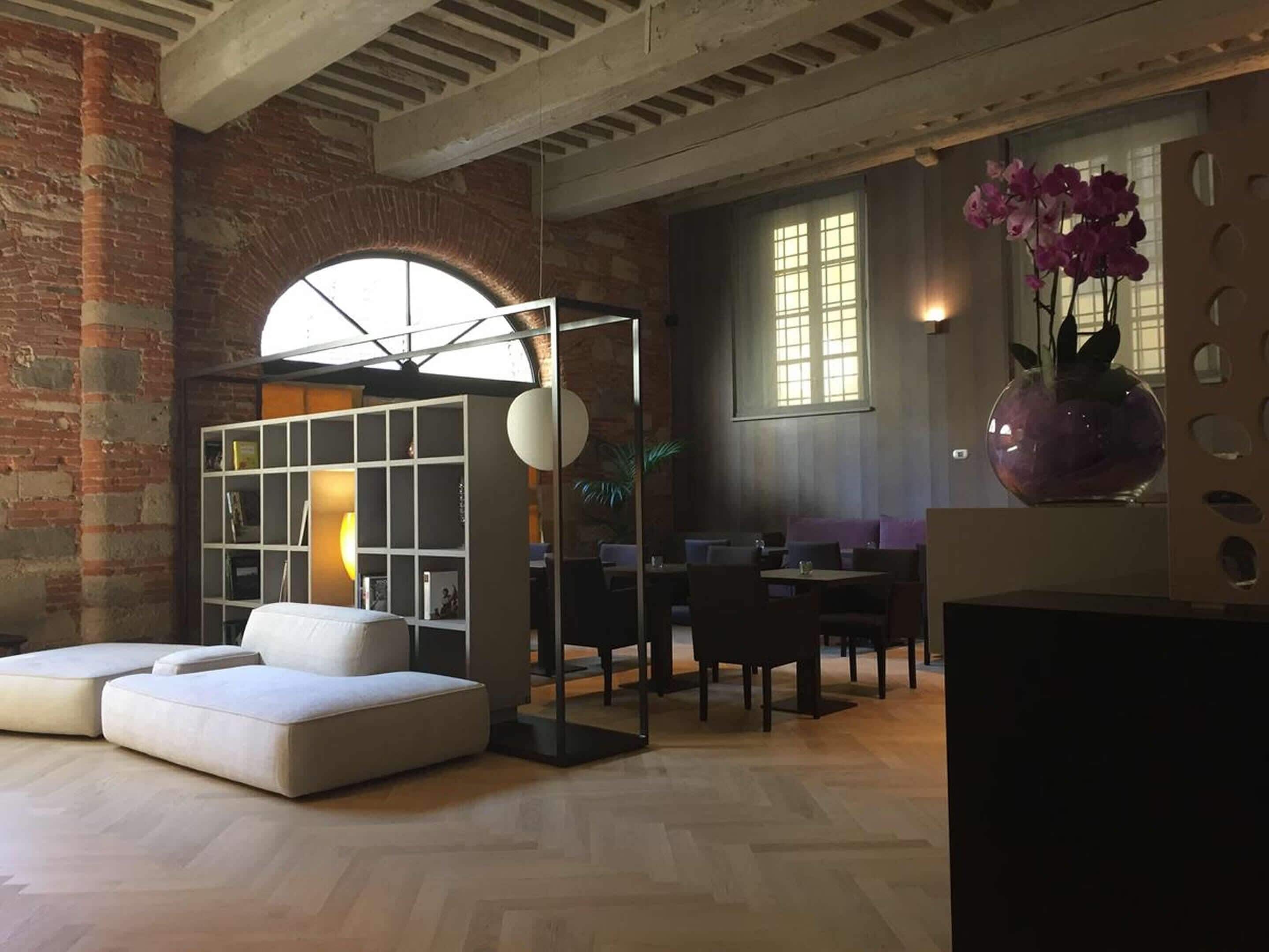 Un salón moderno con un sofá blanco, un separador de vidrio y un comedor con mesas y sillas.