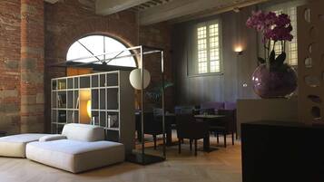 Un salón moderno con un sofá blanco, un separador de vidrio y un comedor con mesas y sillas.