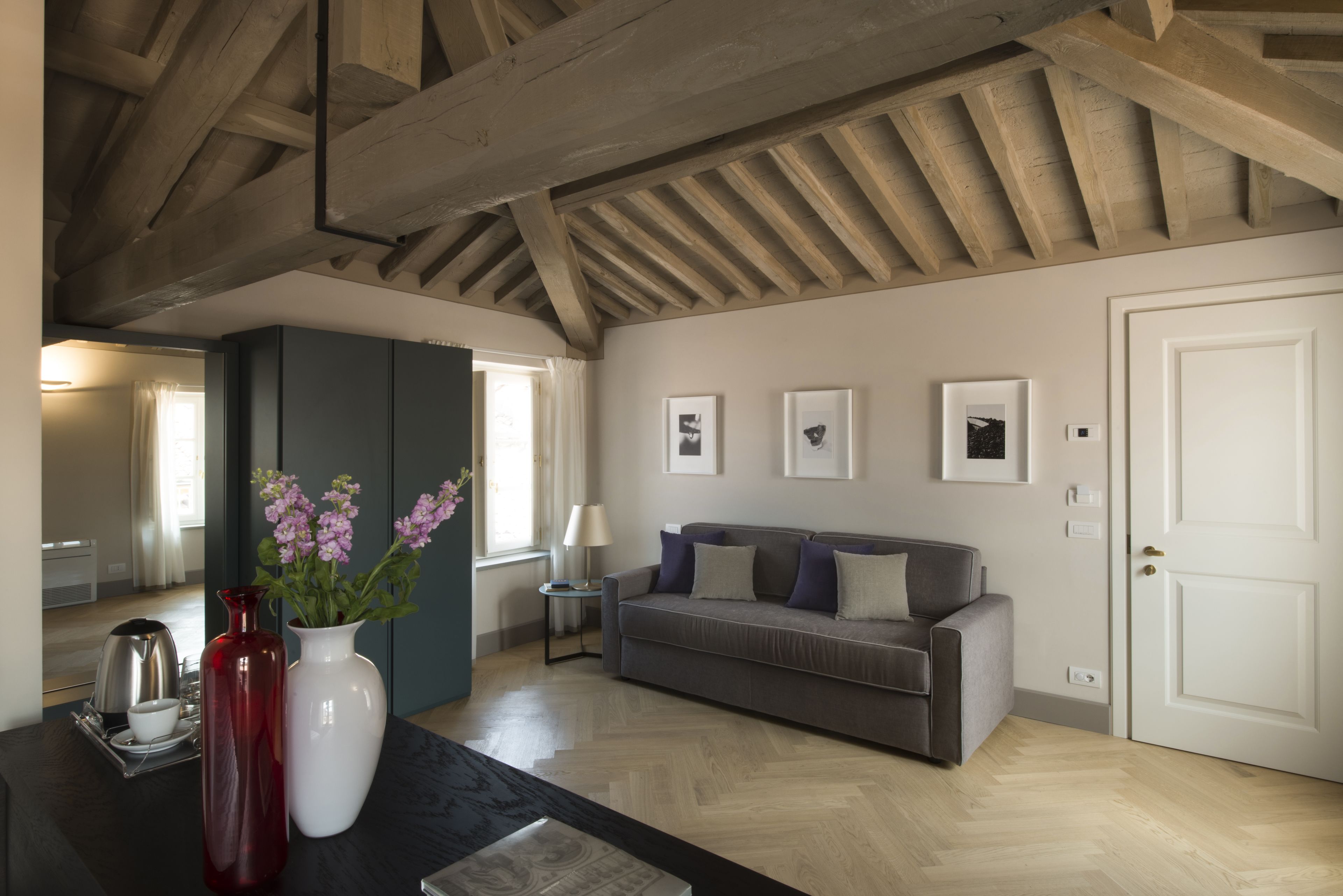 Un salon moderne avec un canapé gris, une porte blanche et des tableaux encadrés accrochés au mur.