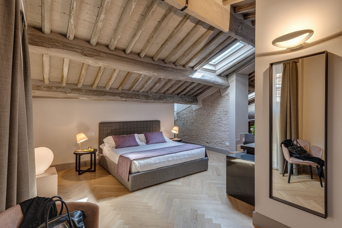 Un dormitorio moderno con una cama grande, una zona de estar y un espejo.