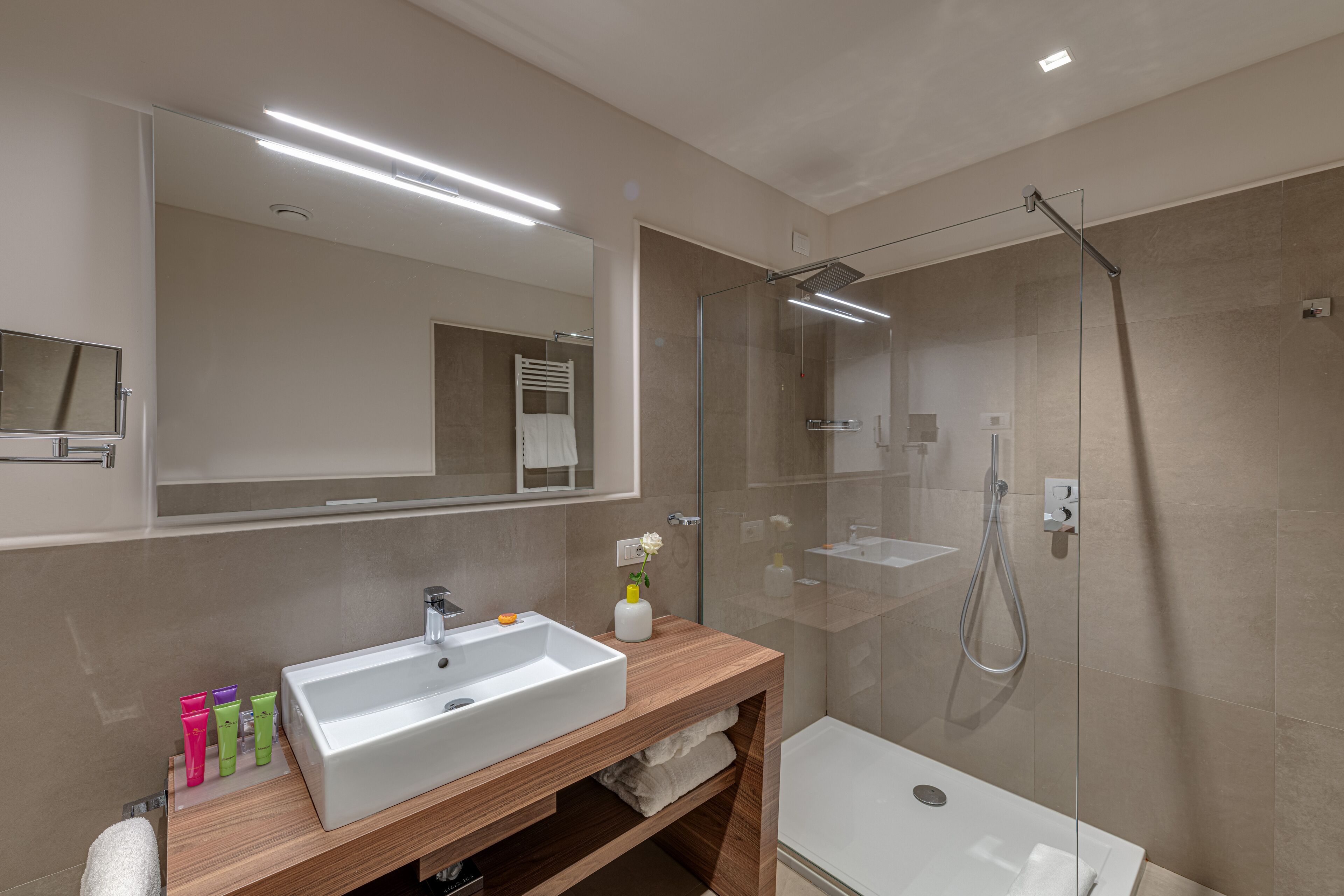 A modern bathroom with a large sink, mirror, and glass-enclosed shower.