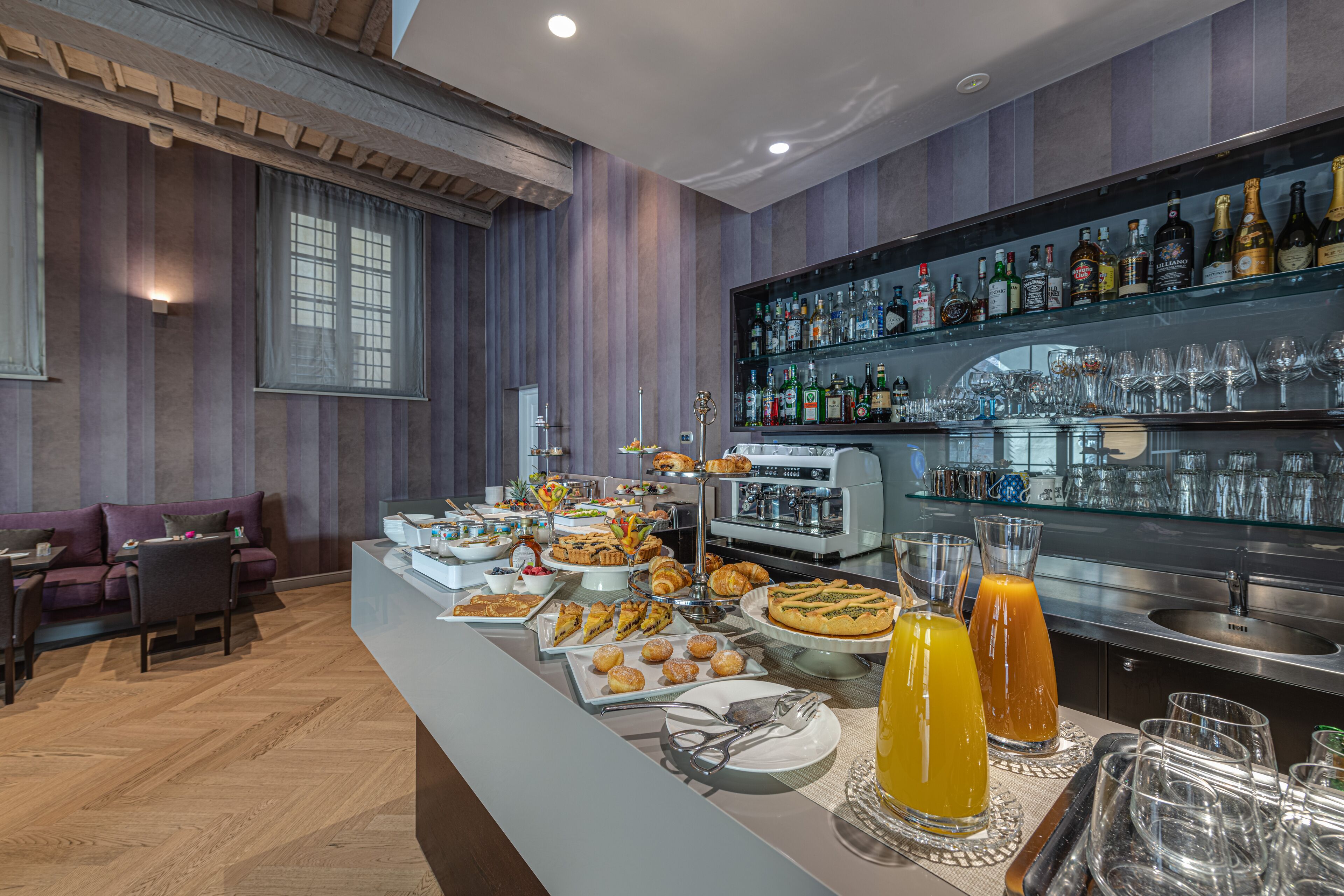 Un buffet proposant une variété de plats et de boissons, un bar avec des bouteilles, et un espace détente avec un canapé et des fauteuils.