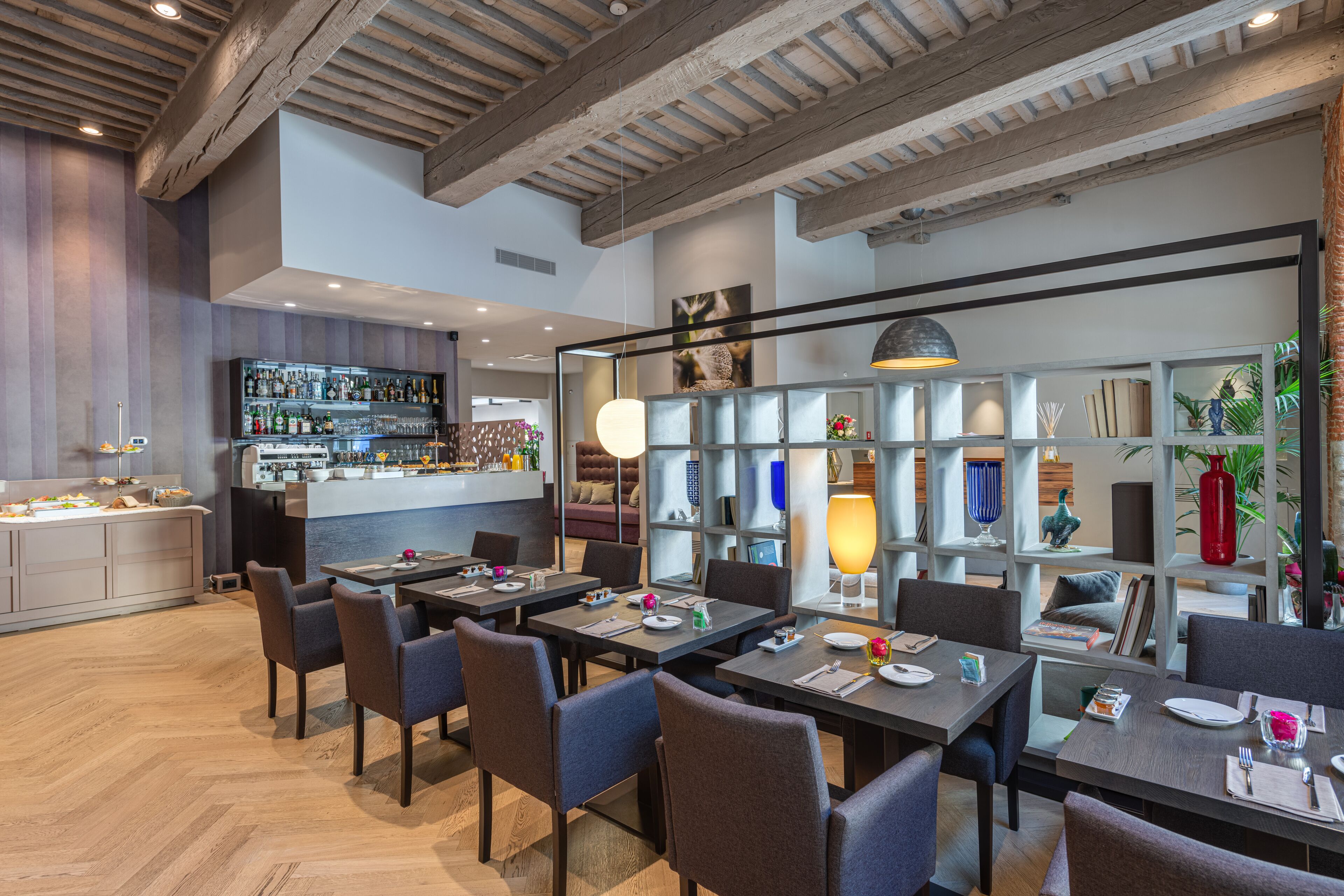 Un ristorante moderno con travi in legno, un'area bar e diverse opzioni di posti a sedere.