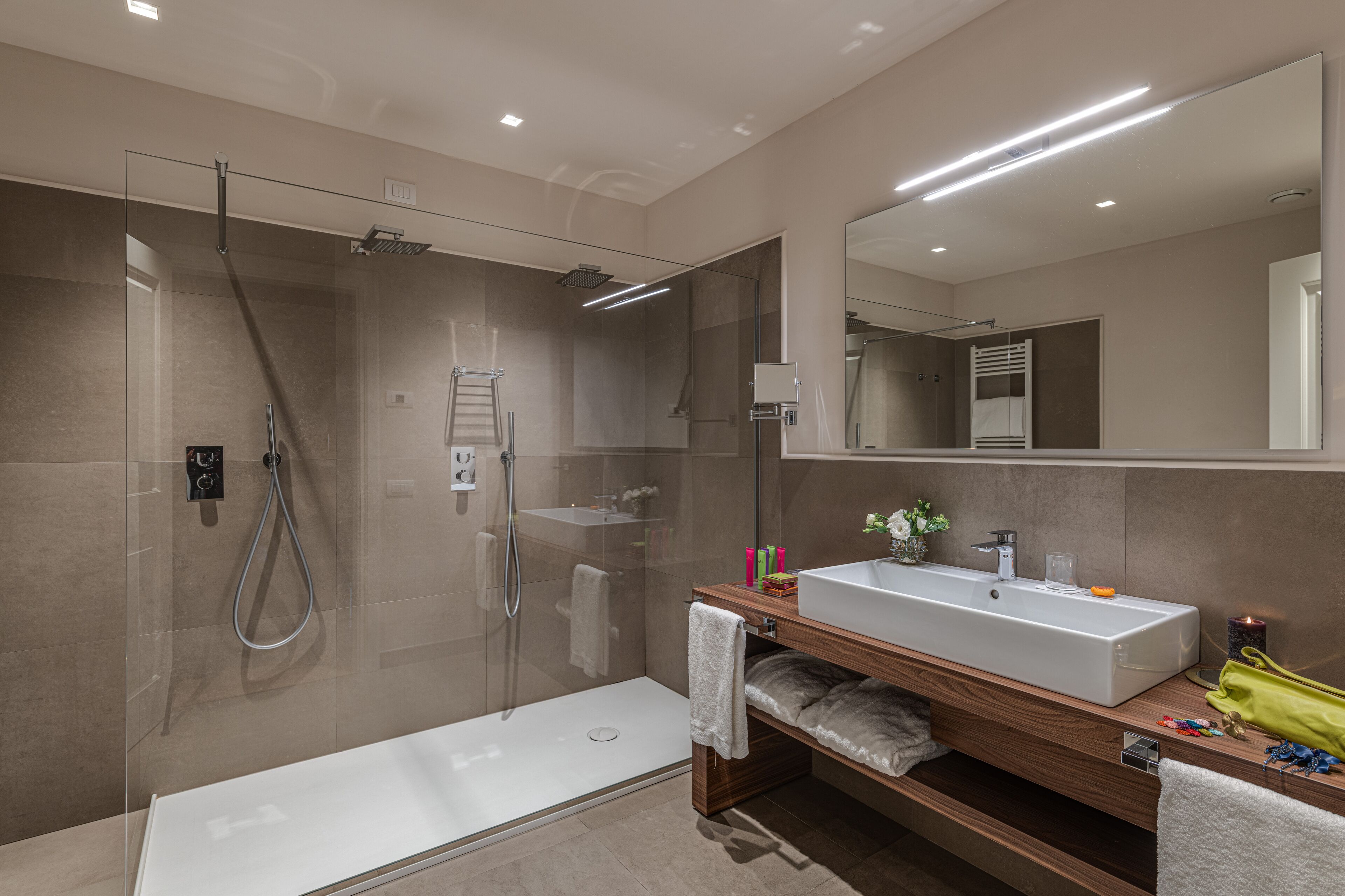 Un baño moderno con ducha envuelta en vidrio, una bañera independiente y un tocador con un espejo grande.