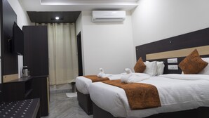 Een hotelkamer met twee bedden, een bureau, een televisie en een airconditioning.