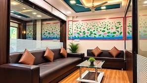 A modern waiting area with leather sofas, a glass coffee table, and a ceiling fan.