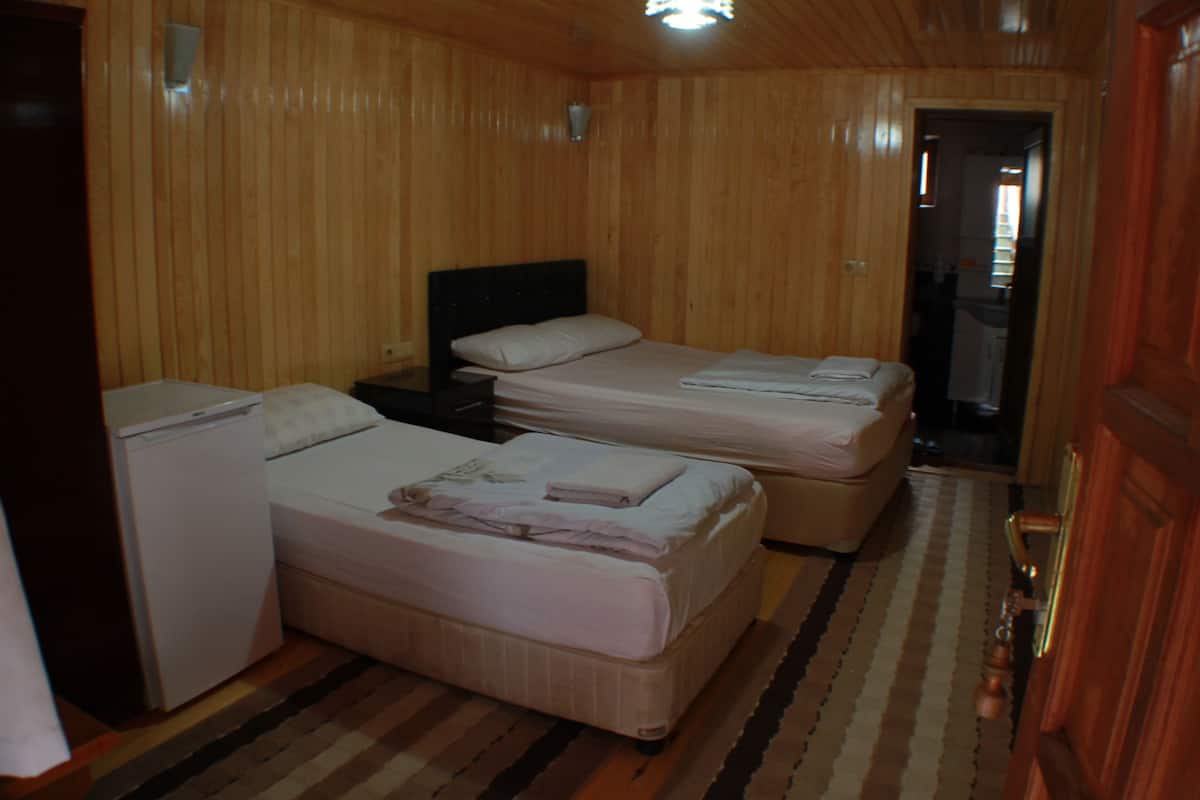 Ein Zimmer mit zwei Betten, einem kleinen Kühlschrank und Holzboden.