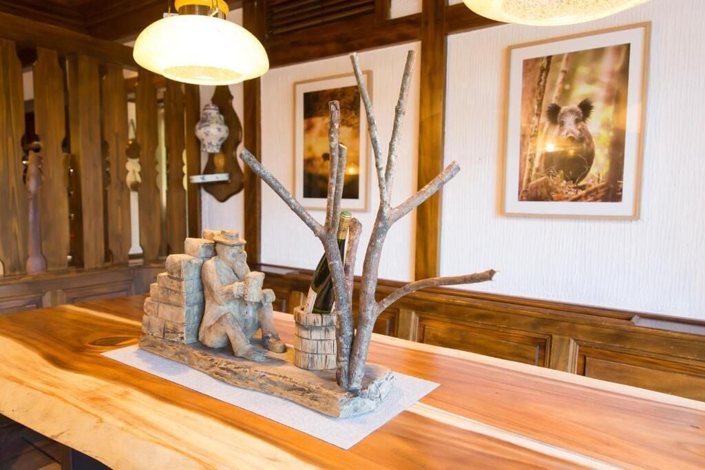 A wooden reception desk with a sculpture of a bear and a tree, a framed picture of a bear, and a hanging light fixture.
