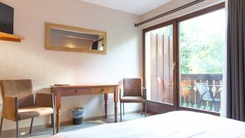 Habitación de hotel con cama, escritorio, dos sillas, televisión y ventana con vistas al exterior.