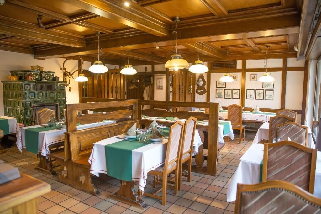 A restaurant with wooden furniture, green tablecloths, and pendant lighting.