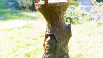 Ein Vogelhaus aus Holz auf einem Baumstumpf in einem Garten.