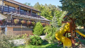 Un immeuble résidentiel doté d’un balcon, d’un toboggan jaune et d’un jardin où poussent différentes espèces de plantes.