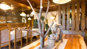L’intérieur d’un restaurant, avec des chaises et des tables en bois, et un arbre décoratif qui sert d’élément central.