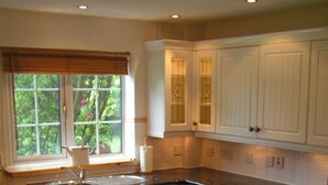 A kitchen with a washing machine, oven, and a window with blinds.