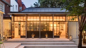 Een modern gebouw met grote glasramen, een trap die leidt naar een zithoek, en twee lantaarns op de trap.