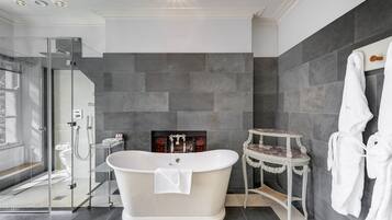 A modern bathroom with a freestanding bathtub, a glass-enclosed shower, and a marble-tiled floor.