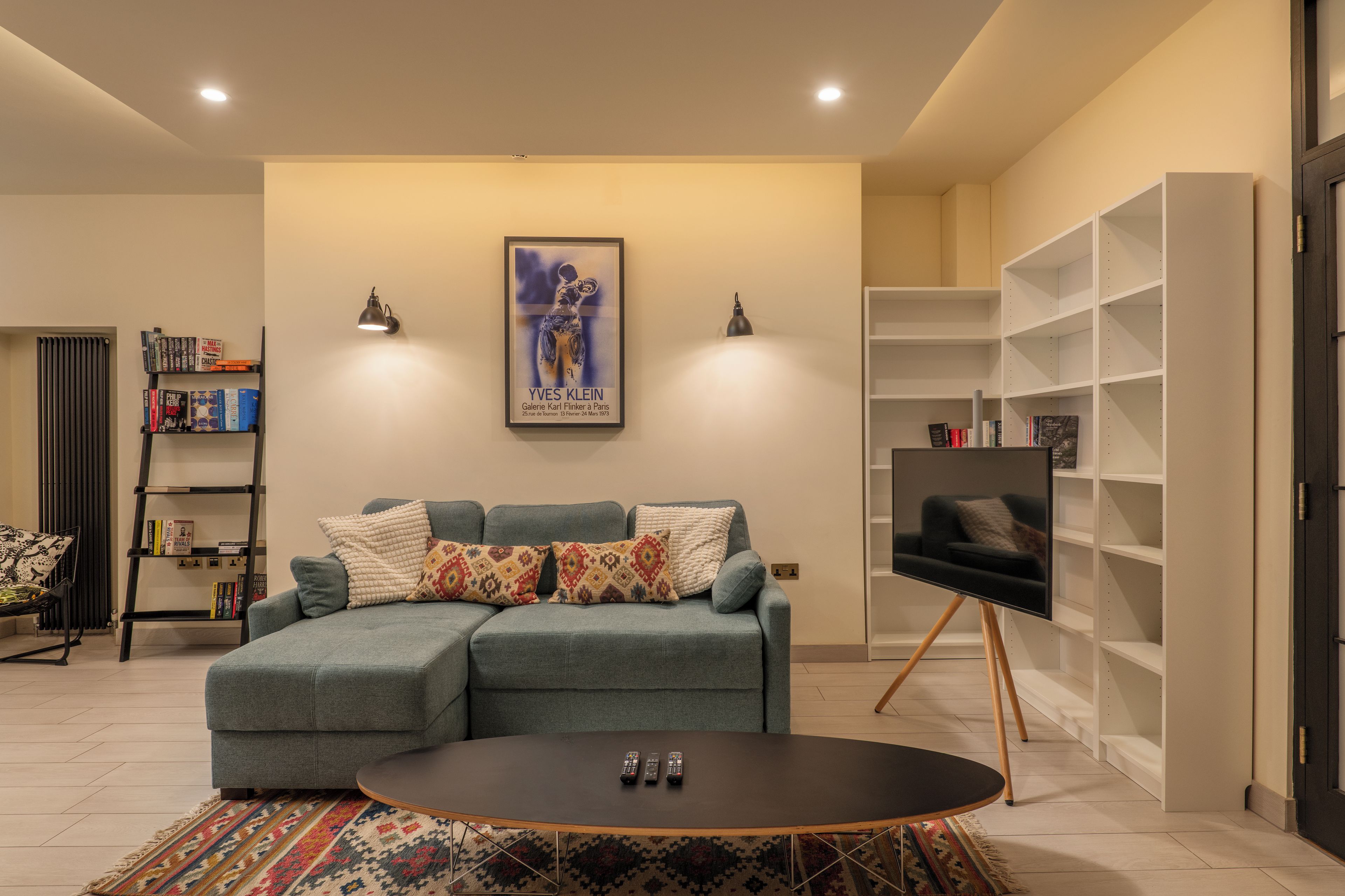 A living room with a sectional sofa, a coffee table, a TV on a stand, and a bookshelf.