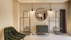 Een moderne badkamer met een witte baksteenmuur, een ronde spiegel en een grijze kast.