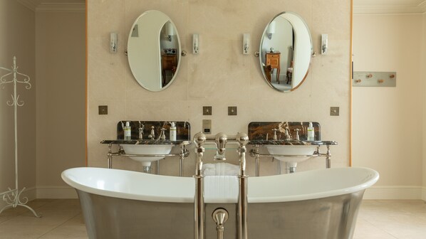 A bathroom with a freestanding bathtub, two sinks, and two wall-mounted mirrors.
