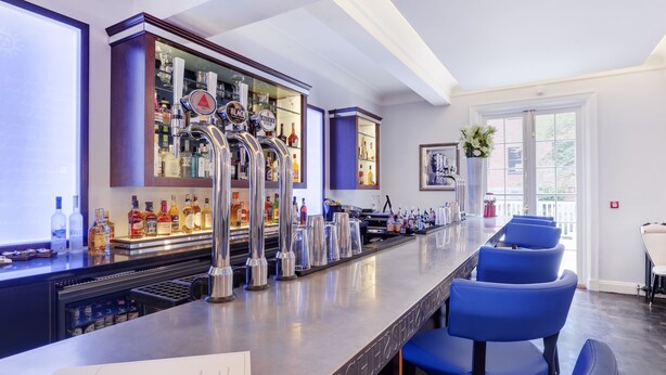 Een bar met een lange toonbank, meerdere tappunten en een menukaart.