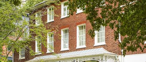 A red brick building with white-framed windows and a covered porch with white railings.