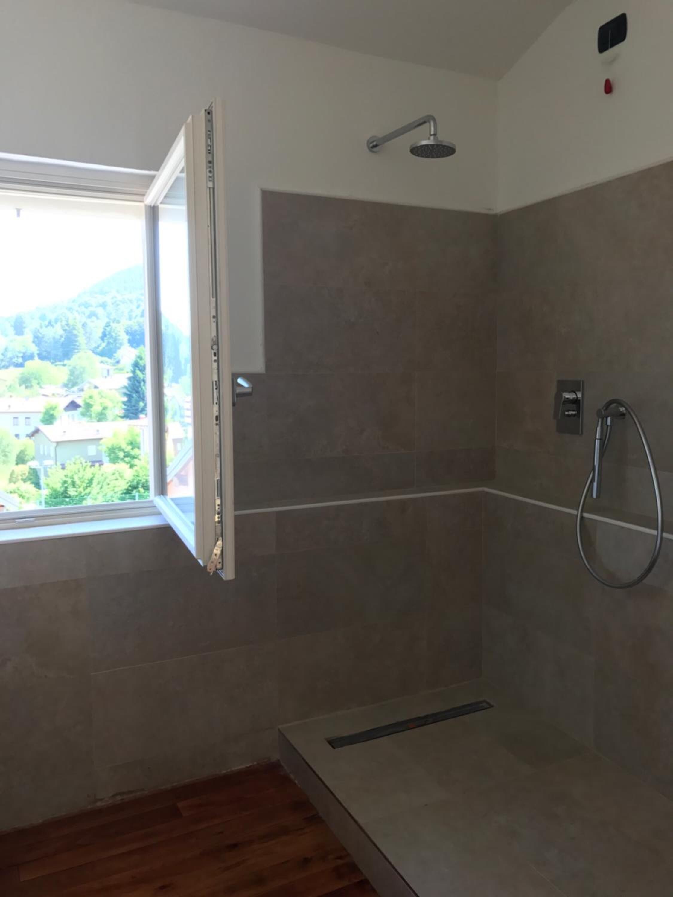 Zona de ducha con ventana, alcachofa y ducha de mano.